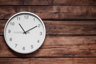 Photo of Stylish round clock on wooden table, top view with space for text. Interior element