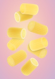 Raw rigatoni pasta falling on pink background