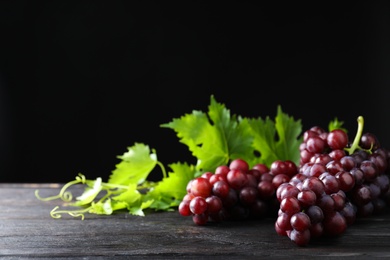 Photo of Fresh ripe juicy grapes on grey table against black background, space for text