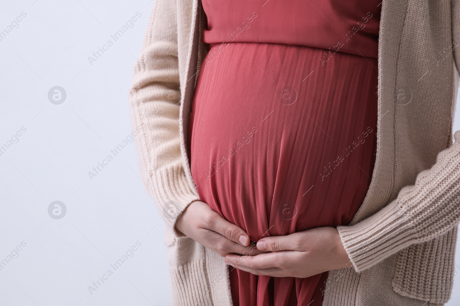 Photo of Young pregnant woman on light background, closeup