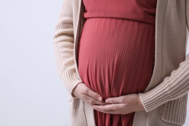Photo of Young pregnant woman on light background, closeup