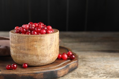 Photo of Cranberries in bowl on wooden table, space for text