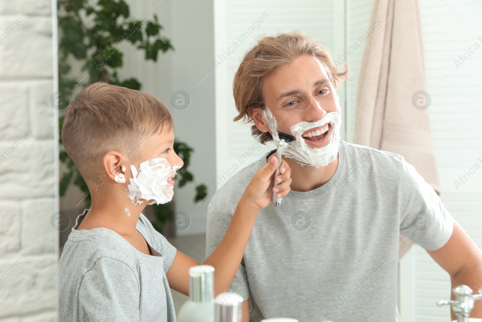 Photo of Father and son shaving together in bathroom