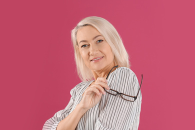 Photo of Portrait of beautiful mature woman with glasses on pink background