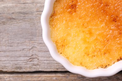 Delicious creme brulee in bowl on wooden table, top view. Space for text