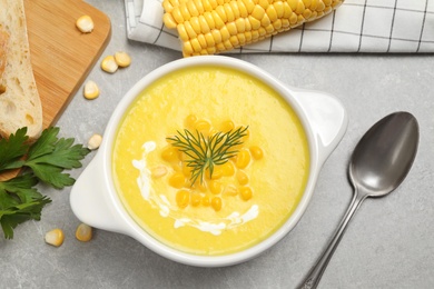 Photo of Delicious creamy corn soup served on grey table, flat lay