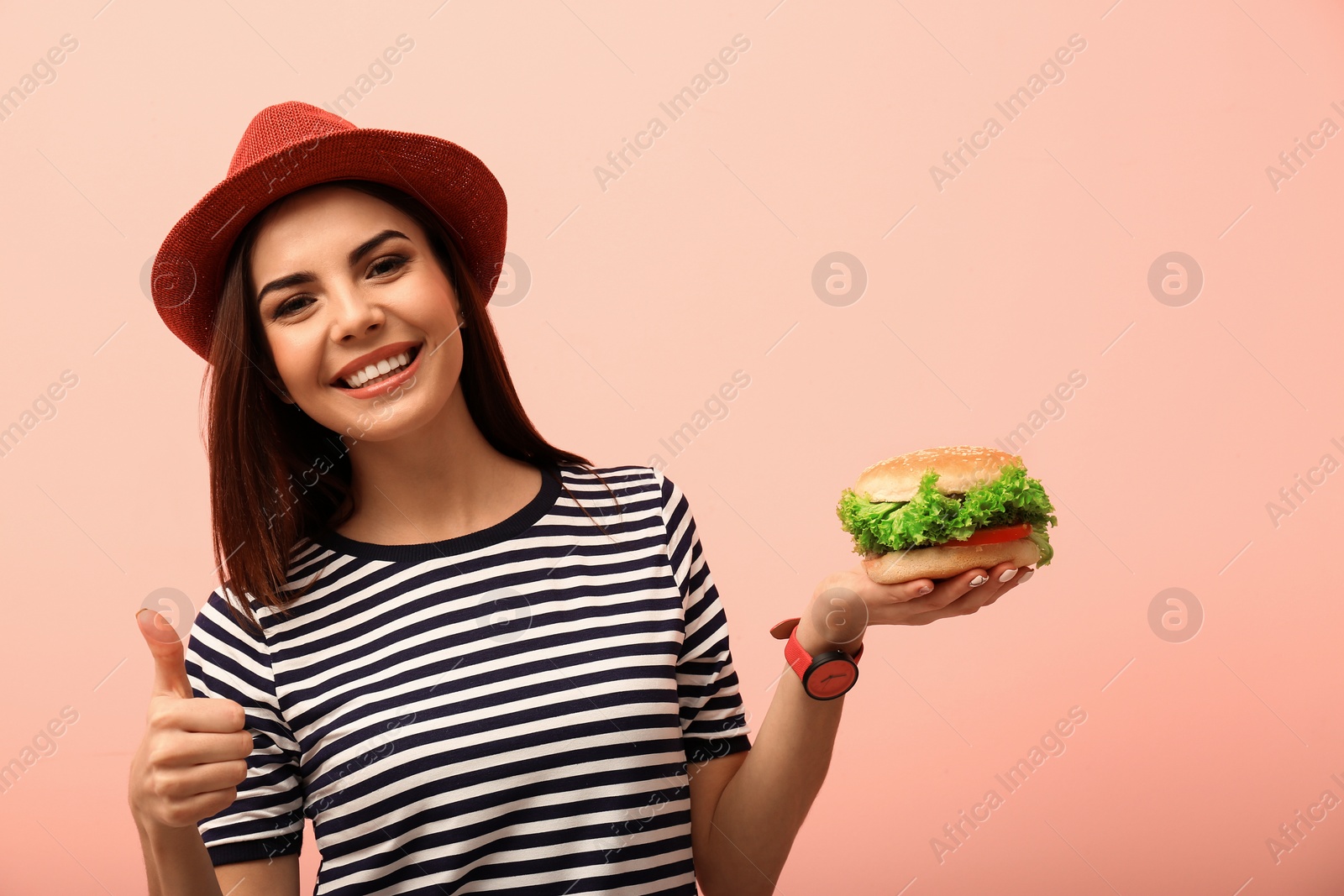 Photo of Young woman with tasty burger on color background. Space for text