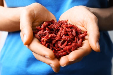 Woman holding red dried goji berries, closeup