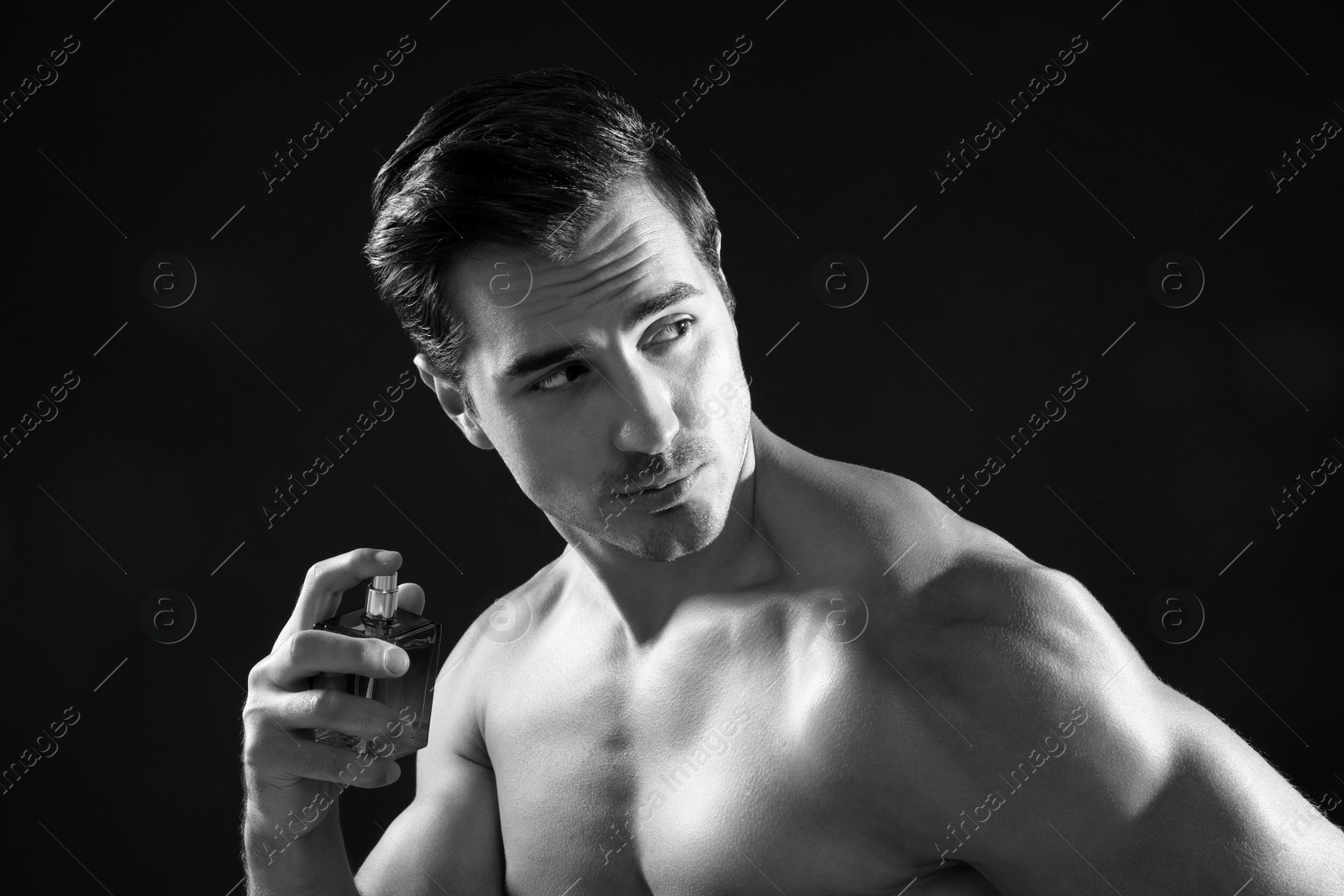 Photo of Handsome young man using perfume, black and white effect