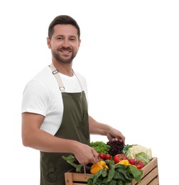 Harvesting season. Happy farmer holding wooden crate with vegetables on white background