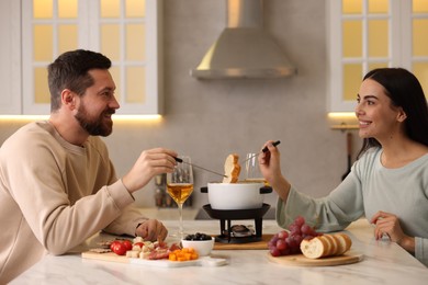 Photo of Affectionate couple enjoying fondue during romantic date in kitchen