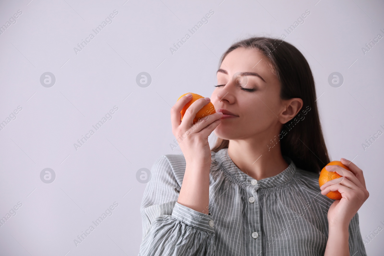 Photo of Woman with fresh tangerines on light grey background. Space for text