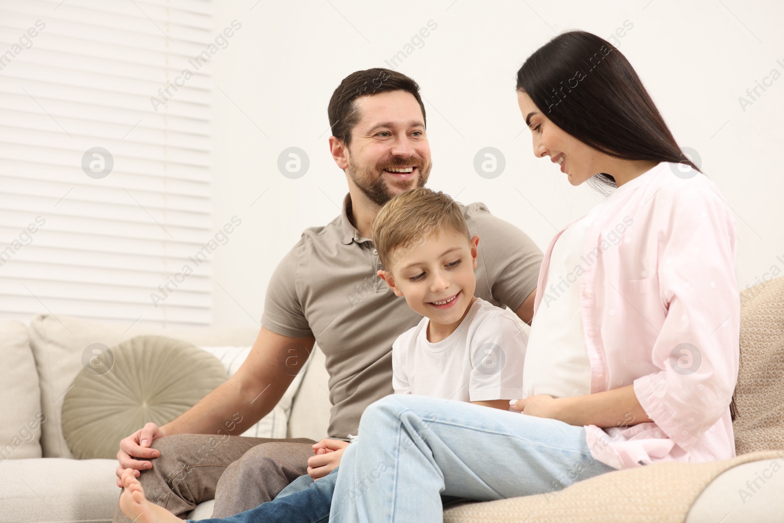 Photo of Happy pregnant woman spending time with her son and husband at home