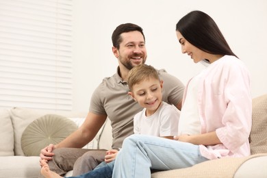 Happy pregnant woman spending time with her son and husband at home