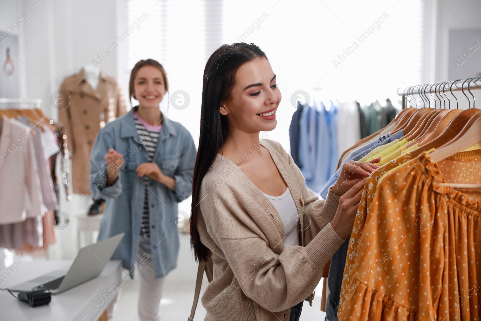 Photo of Shop assistant helping customer to choose clothes in modern boutique