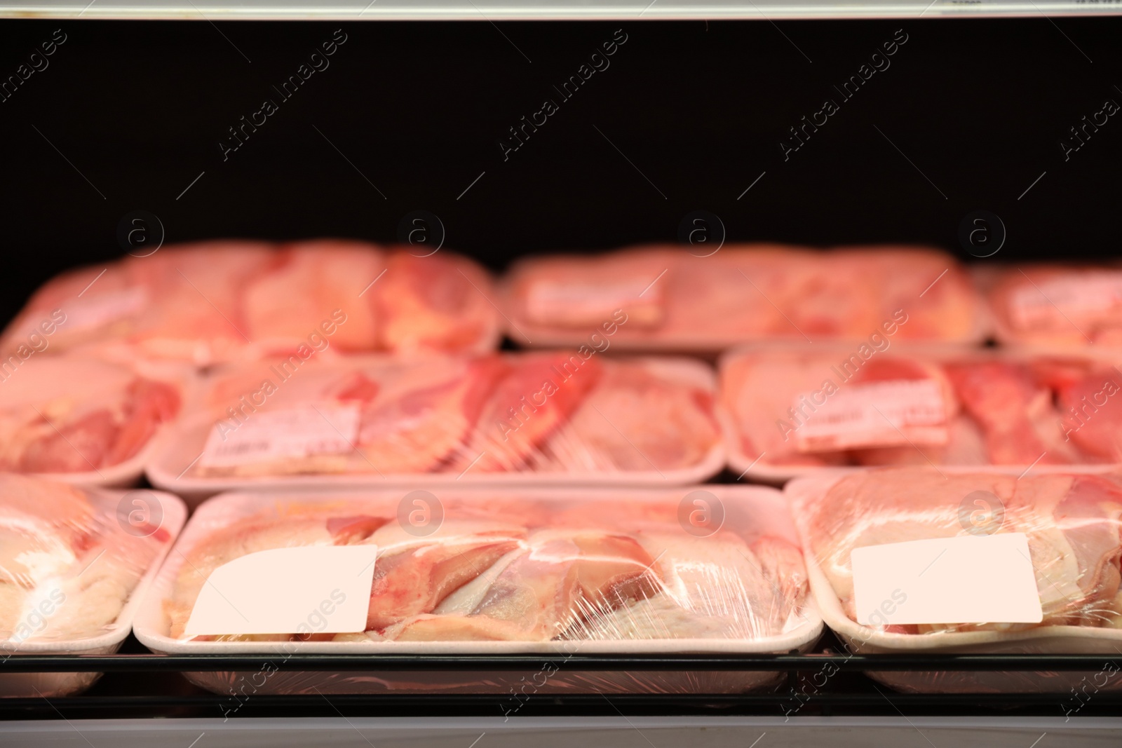 Photo of Shelf with packed chicken meat in supermarket