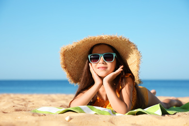 Photo of Cute little child lying at sandy beach on sunny day