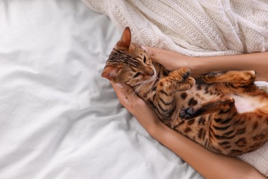 Photo of Woman with cute Bengal cat on bed at home, above view and space for text. Adorable pet