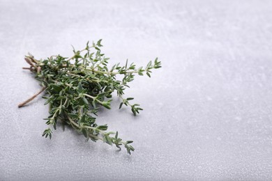 Photo of Bunch of fresh thyme on light grey table, space for text