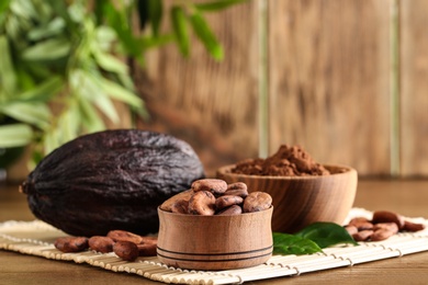 Photo of Bowls of cocoa beans and powder near pod on table