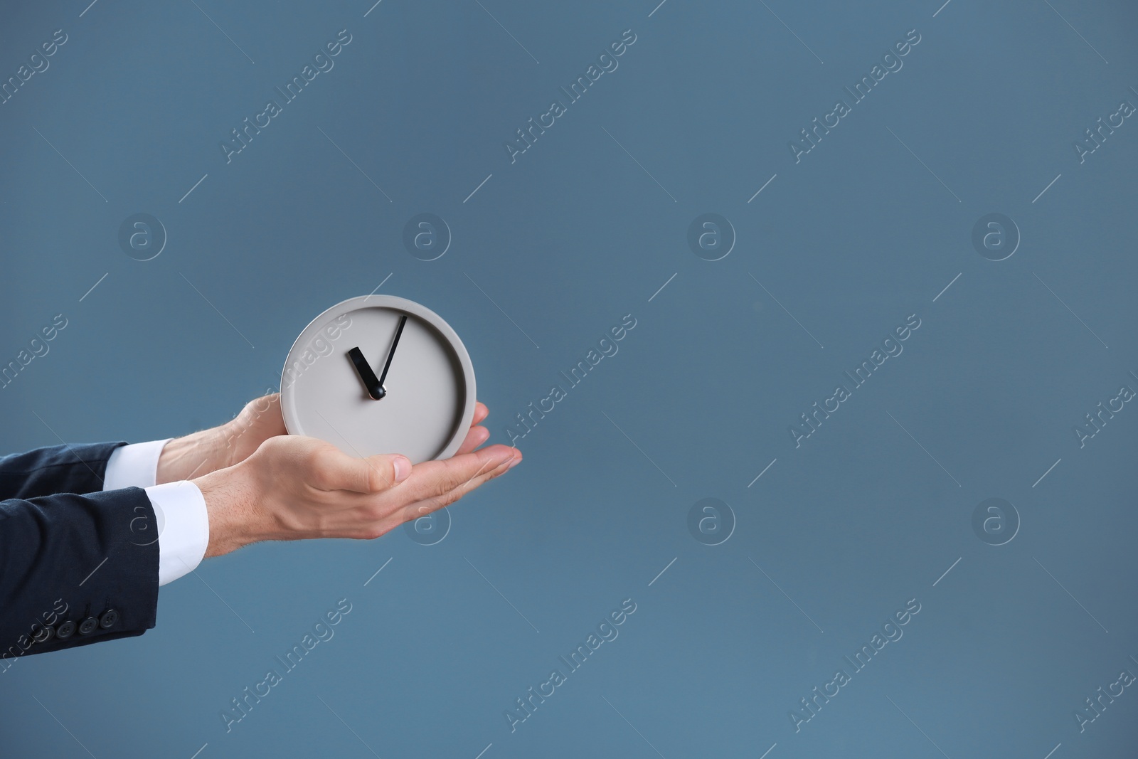 Photo of Businessman holding alarm clock on color background. Time concept
