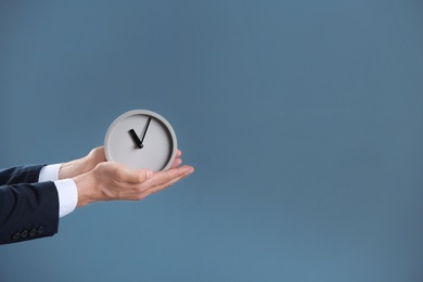 Photo of Businessman holding alarm clock on color background. Time concept