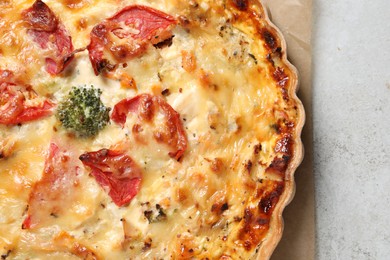 Photo of Tasty quiche with cheese and tomatoes on light grey table, top view