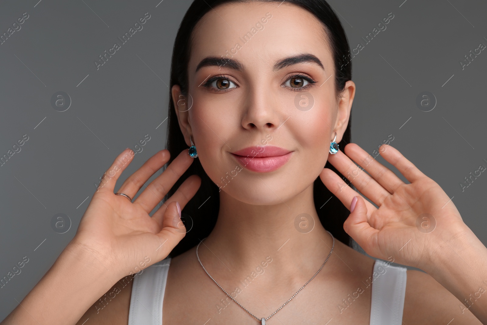 Photo of Beautiful young woman with elegant jewelry on dark grey background