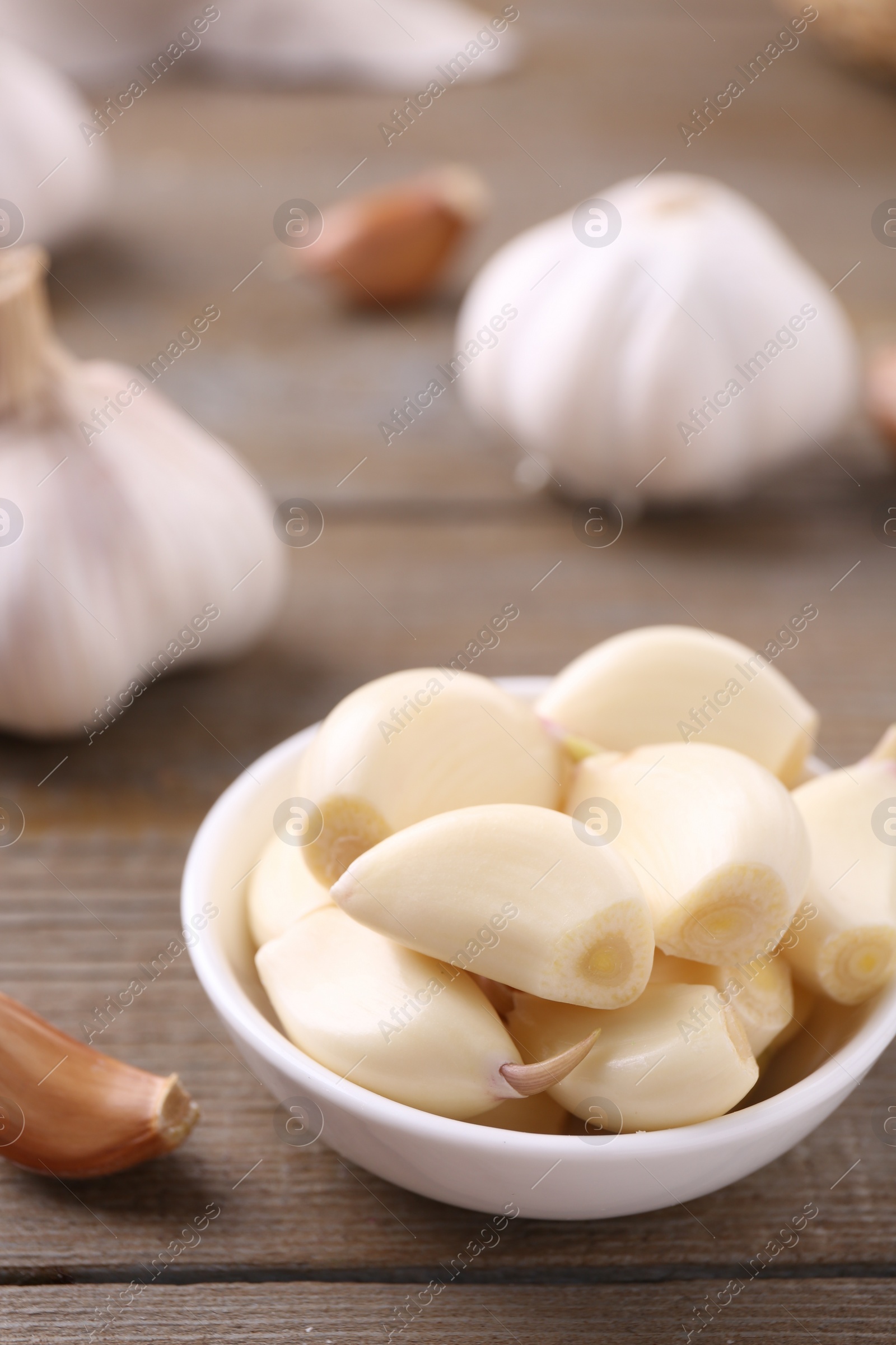 Photo of Aromatic garlic cloves and bulbs on wooden table, closeup. Space for text