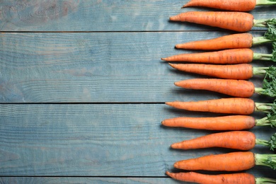 Photo of Fresh carrots on blue wooden table, flat lay. Space for text