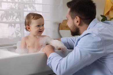 Father washing his little baby in sink at home