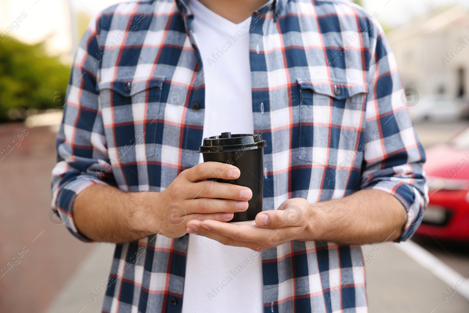 Photo of Man with takeaway coffee cup outdoors, closeup