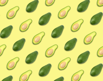 Pattern of whole and halved avocados on pale yellow background