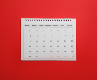 Paper calendar on red background, top view