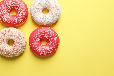 Delicious glazed doughnuts on color background, top view