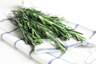 Photo of Fresh green rosemary and napkin on white table