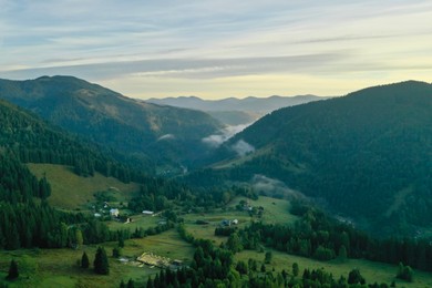 Photo of Aerial view of beautiful mountain landscape with village and green trees in morning