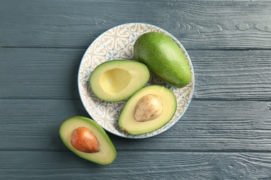 Photo of Plate with ripe avocados on wooden background, top view