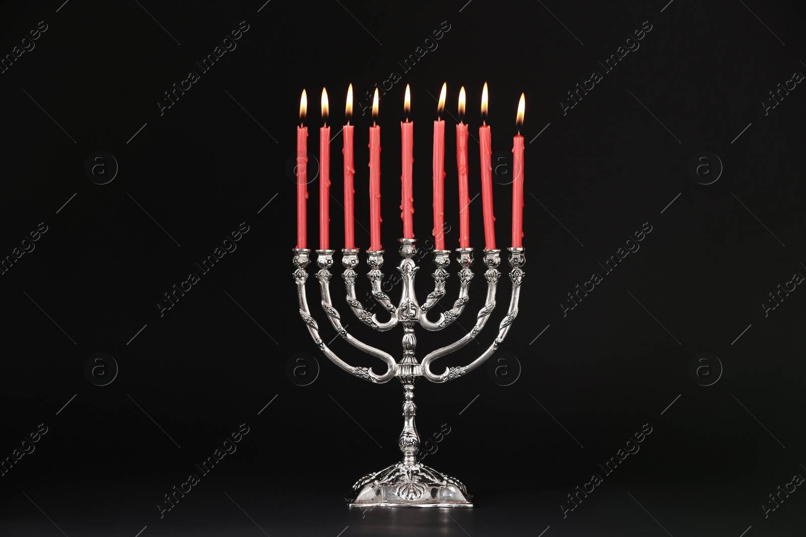 Photo of Silver menorah with burning candles on black background. Hanukkah celebration