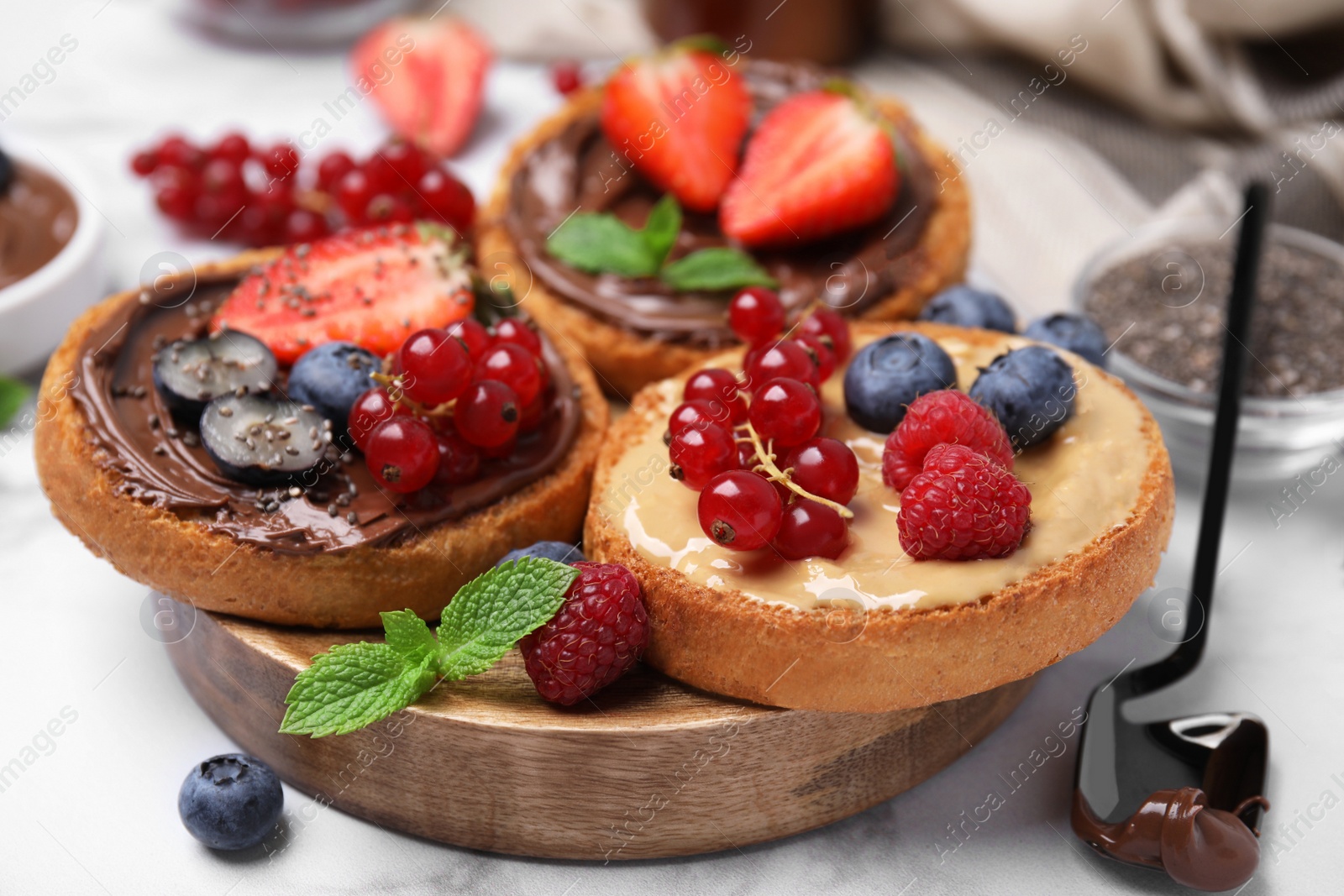 Photo of Tasty organic rusks with different toppings and ingredients on white marble table, closeup