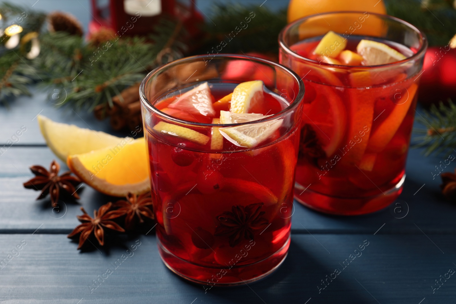 Photo of Delicious punch drink with cranberries and orange on blue wooden table