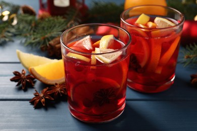 Photo of Delicious punch drink with cranberries and orange on blue wooden table