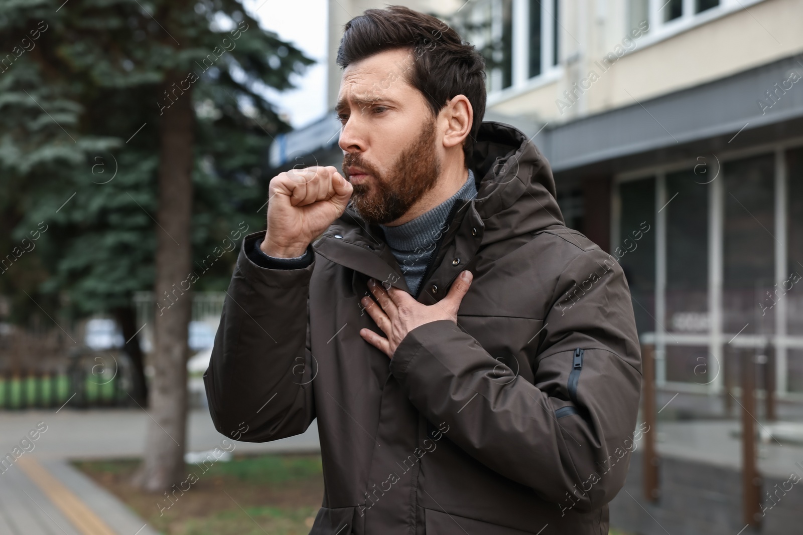 Photo of Sick man coughing on city street. Cold symptoms