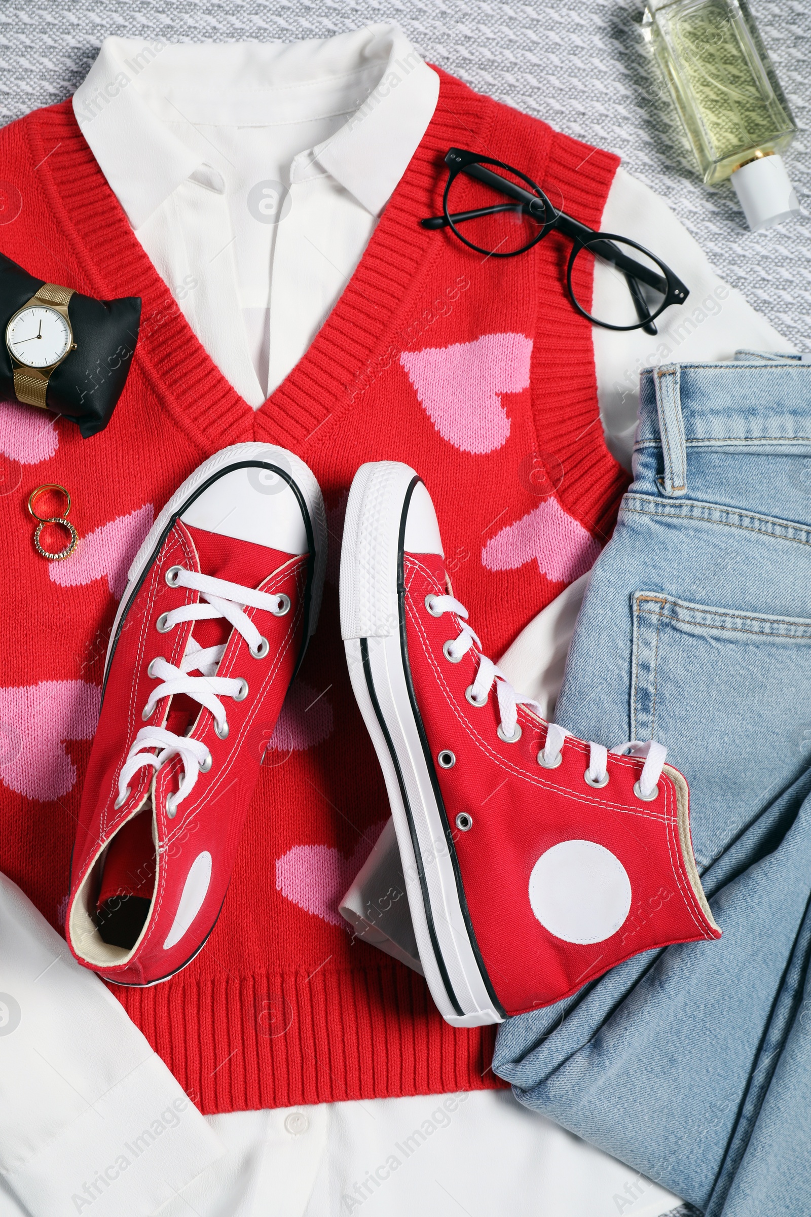 Photo of Pair of stylish red sneakers, clothes and accessories on light grey fabric, flat lay