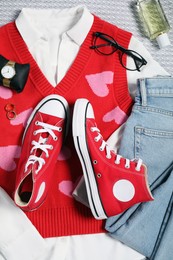 Photo of Pair of stylish red sneakers, clothes and accessories on light grey fabric, flat lay