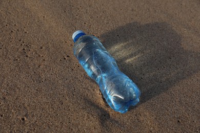 Photo of Plastic bottle of fresh water on wet sand