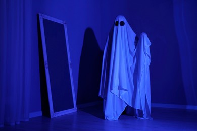 Creepy ghost. Woman covered with sheet in blue light