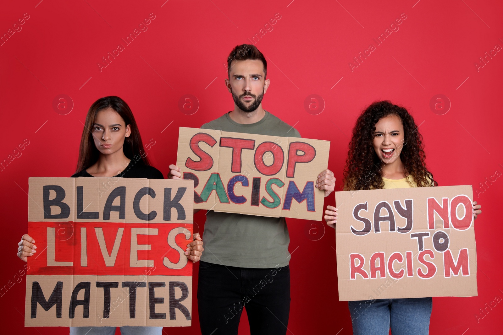 Photo of Protesters demonstrating different anti racism slogans on red background. People holding signs with phrases