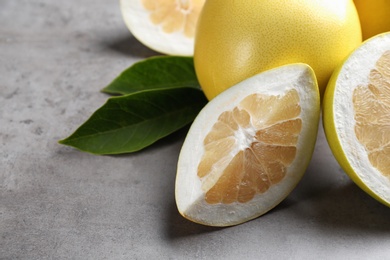 Photo of Fresh cut and whole pomelo fruits on grey table, closeup