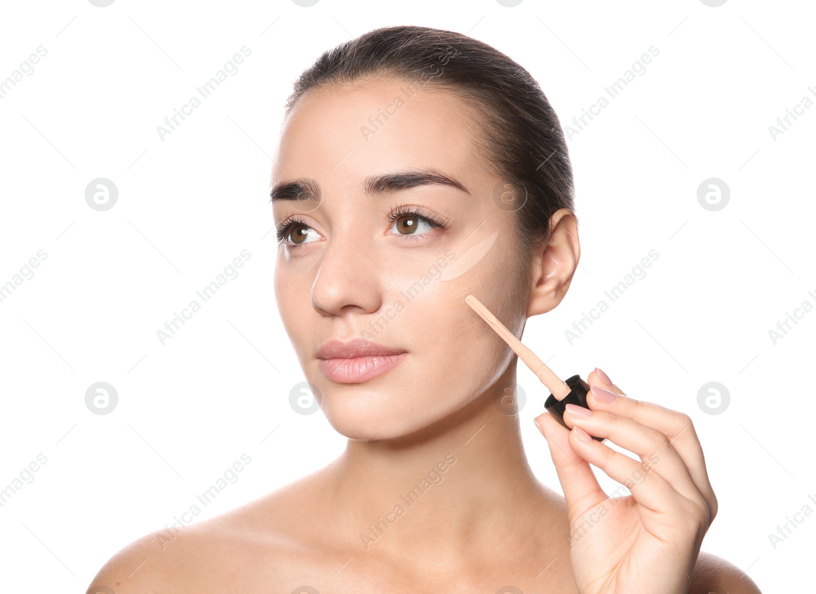 Photo of Young woman applying foundation on her face against white background